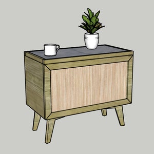 May include: A wooden end table with a light wood finish and a dark gray top. The table has a single door and four legs. A white mug and a potted plant are on the top of the table.