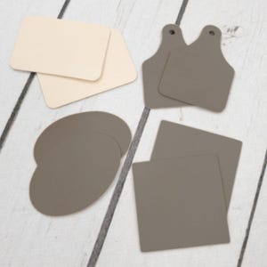 May include: A set of six leather craft shapes in two colors: beige and brown. The shapes include two rectangles, two squares, and two rounded shapes.