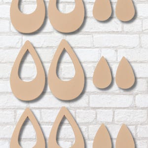 May include: A set of six unfinished wooden teardrop-shaped earrings with different sizes. The earrings have a hole in the top for hanging and a cutout in the center.