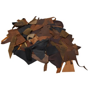 May include: A pile of leather scraps in various shades of brown, black, and tan. The leather pieces are of different sizes and shapes, and some have a distressed or worn look.