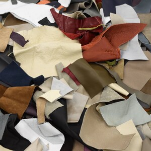 May include: A pile of various leather scraps in different colors, including brown, tan, white, red, and black. The leather scraps are arranged in a random pattern.