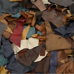May include: A pile of various brown, blue, and red leather scraps. The leather scraps are arranged in a random pattern and are of different sizes and shapes.