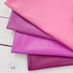 May include: Four stacked layers of smooth, solid-colored fabric in a gradient of pink and purple hues. The top layer is light pink, followed by a medium orchid, a vibrant magenta, and a deep plum shade at the bottom, all featuring a matte finish.