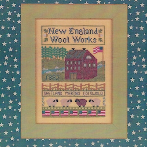 May include: Cross stitch pattern featuring a red barn with a white picket fence, green trees, and a small stream. The pattern also includes a banner that reads "New England Wool Works" and a row of sheep with the text "Shetland Merino Cotswold".