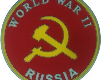 Pode incluir: Um alfinete circular vermelho e amarelo com o texto "WORLD WAR II RUSSIA" ao redor da borda. Um símbolo de martelo e foice amarelo está no centro.