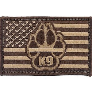 Könnte beinhalten: Ein braunes und beigefarbenes gesticktes Abzeichen mit einem amerikanischen Flaggenmuster und einem Pfotenabdruck mit einer dünnen schwarzen Linie oben und dem Text "K9" unter dem Pfotenabdruck.