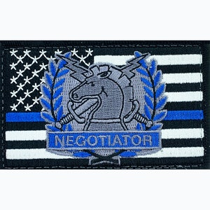 May include: An embroidered patch with a blue line American flag background. The patch features a gray horse with a sword in each hand, a lightning bolt above its head, and a laurel wreath on either side. The text "NEGOTIATOR" is written in a banner below the horse.