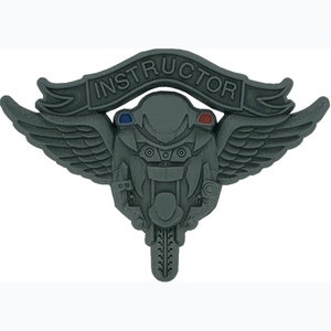 May include: A silver-colored motorcycle instructor badge with wings and the word "INSTRUCTOR" on a banner above the motorcycle. The motorcycle has red and blue lights on the front.