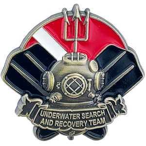May include: A gold-toned metal pin with a diving helmet, two black scuba fins, a red and white scuba flag, and a trident. The pin has a banner that reads "UNDERWATER SEARCH AND RECOVERY TEAM".