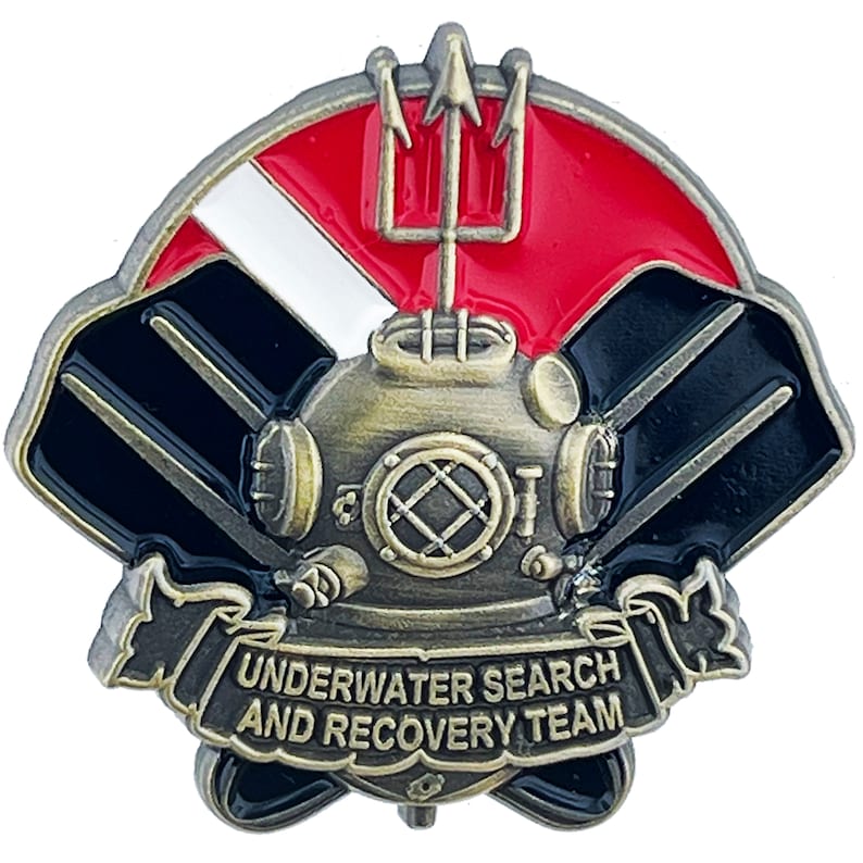 May include: A gold-toned metal pin with a diving helmet, two black scuba fins, a red and white scuba flag, and a trident. The pin has a banner that reads "UNDERWATER SEARCH AND RECOVERY TEAM".