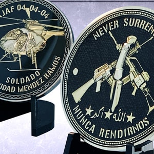 May include: Two gold-colored challenge coins with black backgrounds. The first coin features a helicopter with the text "AN NAJAF 04-04-04 NATIVIDAD SOLDADO MENDEZ RAMOS". The second coin features crossed rifles with the text "NEVER SURRENDER  MUCA RENDIRNOS  *الله*  *N* *I* *"