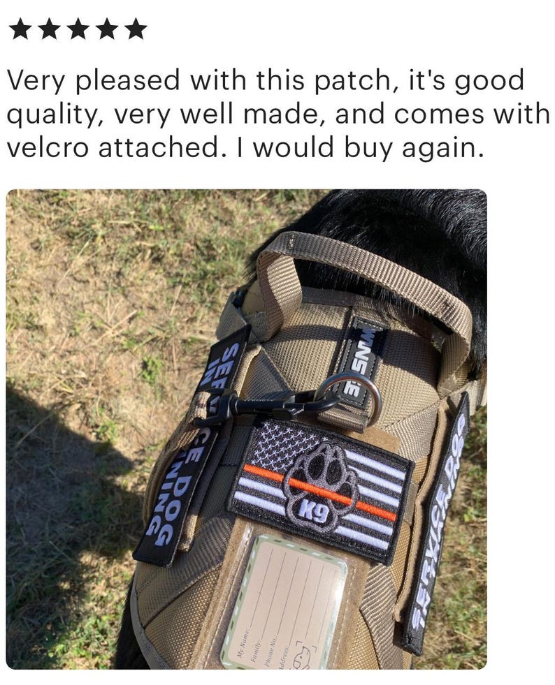 May include: A tan service dog vest with black straps and a black handle. The vest has a black and white American flag patch with a red paw print and the word "K9" in white. The vest also has two patches that say "Service Dog" and "K9" in white.