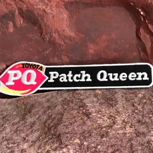May include: A black and white embroidered patch with the text "Patch Queen" and a red, yellow, and white logo with the text "PQ" and "Toyota" on it.
