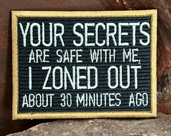 May include: Black embroidered patch with gold stitching around the edges. The text reads "Your secrets are safe with me, I zoned out about 30 minutes ago."