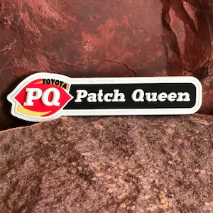 Puede incluir: Parche blanco con texto negro que dice "Patch Queen" y un logotipo rojo y amarillo con el texto "PQ" y "TOYOTA" en negro.