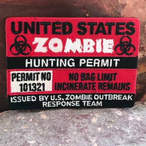 Puede incluir: Un parche bordado rojo y negro con el texto "UNITED STATES ZOMBIE HUNTING PERMIT" y "PERMIT NO 101321 NO BAG LIMIT INCINERATE REMAINS". El parche también incluye un símbolo de riesgo biológico y el texto "ISSUED BY U.S. ZOMBIE OUTBREAK RESPONSE TEAM".