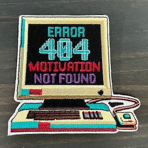 Könnte beinhalten: Gestickter Patch eines Retro-Computers mit dem Text "ERROR 404 MOTIVATION NOT FOUND" auf dem Bildschirm. Der Computer ist weiß mit einer braunen Tastatur und einem türkisfarbenen und roten Rand.
