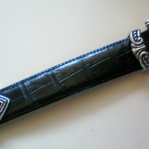 Peut inclure: Une ceinture en cuir noir avec une boucle argent&eacute;e et des accents en forme de c&oelig;ur. La boucle a un design d&eacute;coratif.