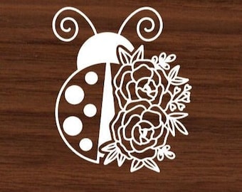 May include: A white silhouette of a ladybug with black spots and a floral design. The ladybug has a pair of antennae and the floral design includes two large flowers and smaller leaves.