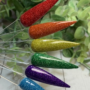May include: Six different colors of glitter nail polish displayed on clear plastic applicators. The colors are red, orange, yellow, green, purple, and blue.
