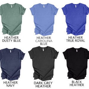 May include: Six heather t-shirts in various colors: dusty blue, Carolina blue, true royal, navy, dark grey heather, and black heather. Each shirt is displayed flat, showcasing the crew neck and short sleeves. The text on the image identifies the color of each shirt.