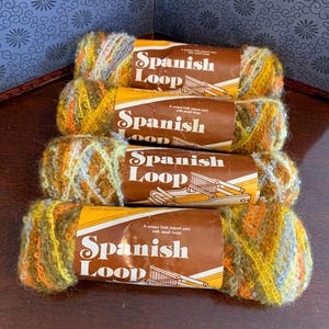 May include: Four skeins of Spanish Loop yarn in shades of yellow, orange, and green. Each skein has a brown label with the text "Spanish Loop" and a graphic of a weaving tool. The yarn is a unique Irish import.