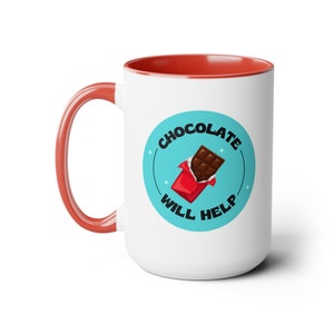 Puede incluir: Taza de cerámica blanca con borde rojo. La taza tiene un círculo azul con el texto "Chocolate Will Help" y una imagen de dibujos animados de una barra de chocolate en un envoltorio rojo.