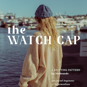 May include: A knitting pattern cover with the text "the WATCH CAP". A person wears a blue knitted watch cap and a beige sweater. The text "A KNITTING PATTERN by blaksands" is also visible. The pattern is for advanced beginners to intermediate knitters.