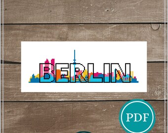 May include: Counted cross stitch pattern for a Berlin skyline with the word "BERLIN" in colorful letters. The pattern is 56 x 140 stitches and is recommended for 14 count Aida fabric, measuring 4 inches by 10 inches.