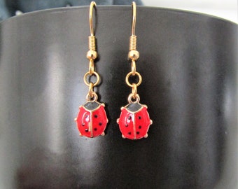May include: A pair of gold dangle earrings with red and black ladybug charms.