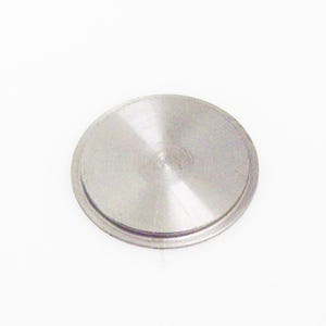 May include: A circular, silver-colored metal object with a slightly raised edge. The surface has a brushed texture and a central indentation. The object is set against a plain white background.