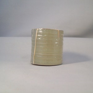 May include: A stack of clear, round, plastic discs wrapped in plastic wrap. The discs are stacked on top of each other and are held together by a rubber band.