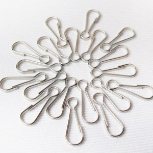May include: A close-up of a group of silver key rings arranged in a circular pattern on a white surface.