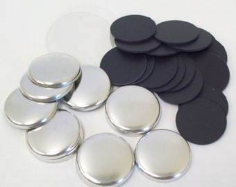 May include: A set of silver-colored snap fasteners, with a pile of black fabric circles.