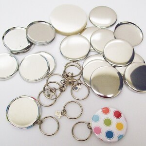 May include: A set of silver metal button blanks for making custom buttons. The set includes a variety of sizes and a keychain with a colorful polka dot button.