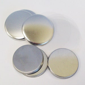 Puede incluir: Primer plano de seis botones redondos de metal de color plateado.