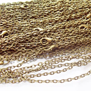 May include: A close-up of a pile of gold-colored chain links. The chain is made of metal and has a smooth, shiny finish.