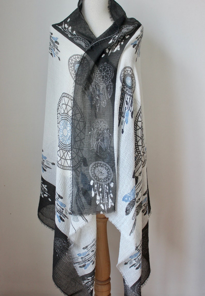 K&ouml;nnte beinhalten: Ein schwarz-wei&szlig;er Schal mit einem Traumf&auml;nger-Muster. Der Schal ist aus einem weichen, leichten Stoff gefertigt und perfekt, um jedem Outfit einen Hauch von Boho-Stil zu verleihen.