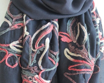 Puede incluir: Una bufanda azul oscuro con detalles bordados de colores. El bordado está hecho de hilo grueso en tonos de rosa, crema y verde.