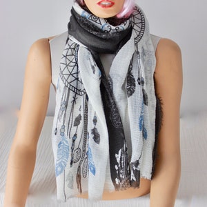 K&ouml;nnte beinhalten: Ein wei&szlig;er und schwarzer Schal mit einem Traumf&auml;nger- und Federmuster. Der Schal ist aus einem weichen, leichten Stoff gefertigt und perfekt, um jedem Outfit einen Hauch von Boho-Stil zu verleihen.