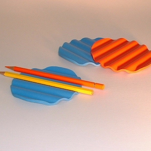 Puede incluir: Dos posavasos redondos ondulados y texturizados, azul y naranja, con tres l&aacute;pices encima de uno de los posavasos.