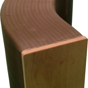 May include: A curved wooden bench with a light brown finish. The bench has a smooth, rounded surface and a slightly textured grain pattern.