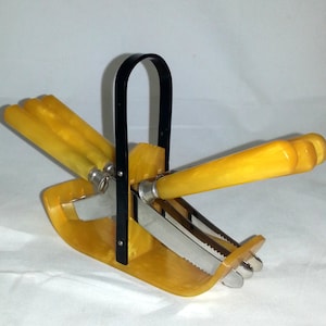 May include: A set of four yellow butter knives with black handles in a yellow plastic holder with a black handle.