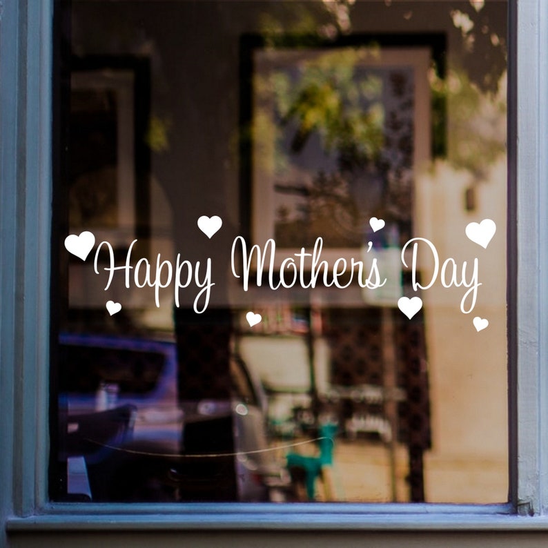 May include: White vinyl decal with the text "Happy Mother's Day" and small hearts surrounding the text. The decal is applied to a glass window.