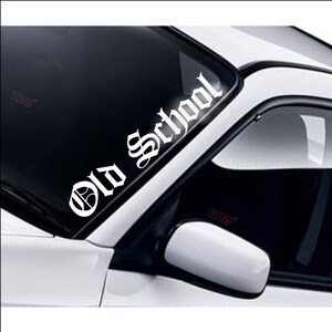 May include: White vinyl decal sticker with the words "Old School" in a gothic font. The sticker is placed on the windscreen of a car.