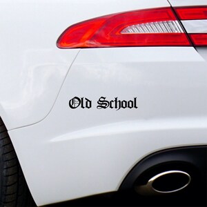 May include: A white car with a black "Old School" decal on the rear bumper.
