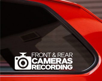 May include: White sticker on a red car window that says "Front & Rear Cameras Recording" with a camera icon.