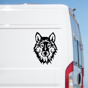 May include: Black and white silhouette of a wolf's head, facing forward, with a detailed design of fur and facial features. The wolf head is on a white background.