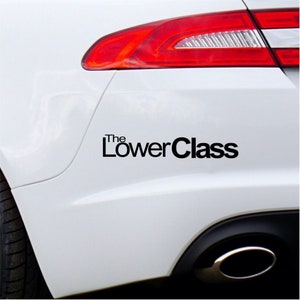 May include: A white car with a black decal that says "The LowerClass" on the rear bumper.