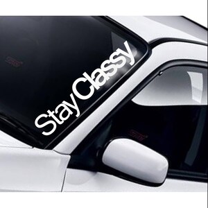 May include: White vinyl decal sticker with the text "Stay Classy" on a white car windscreen.